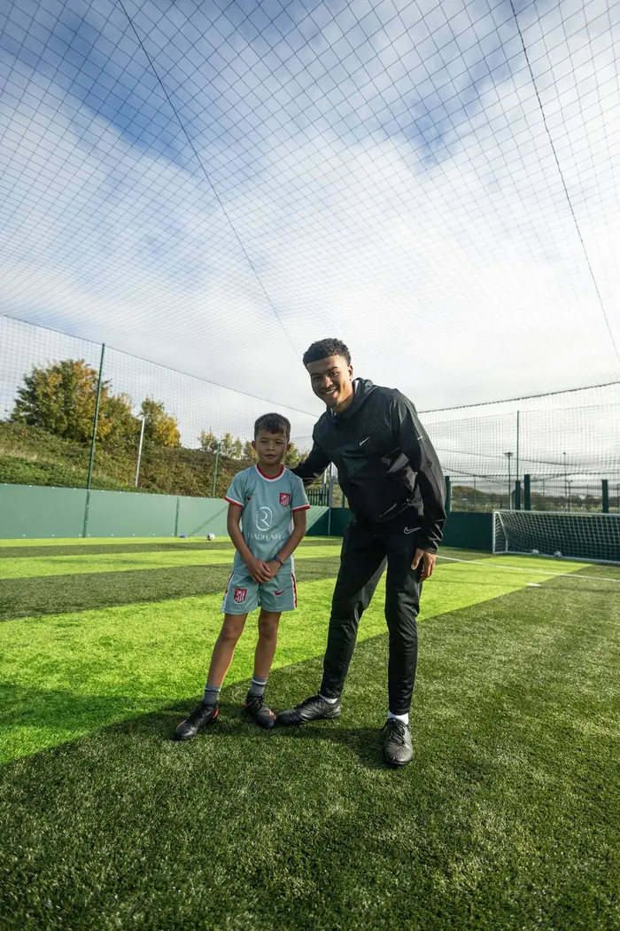 The coach and a young player smiling together on the pitch