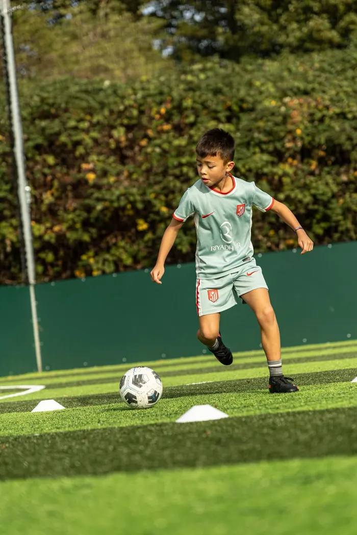 A young player dribbling the ball around cones